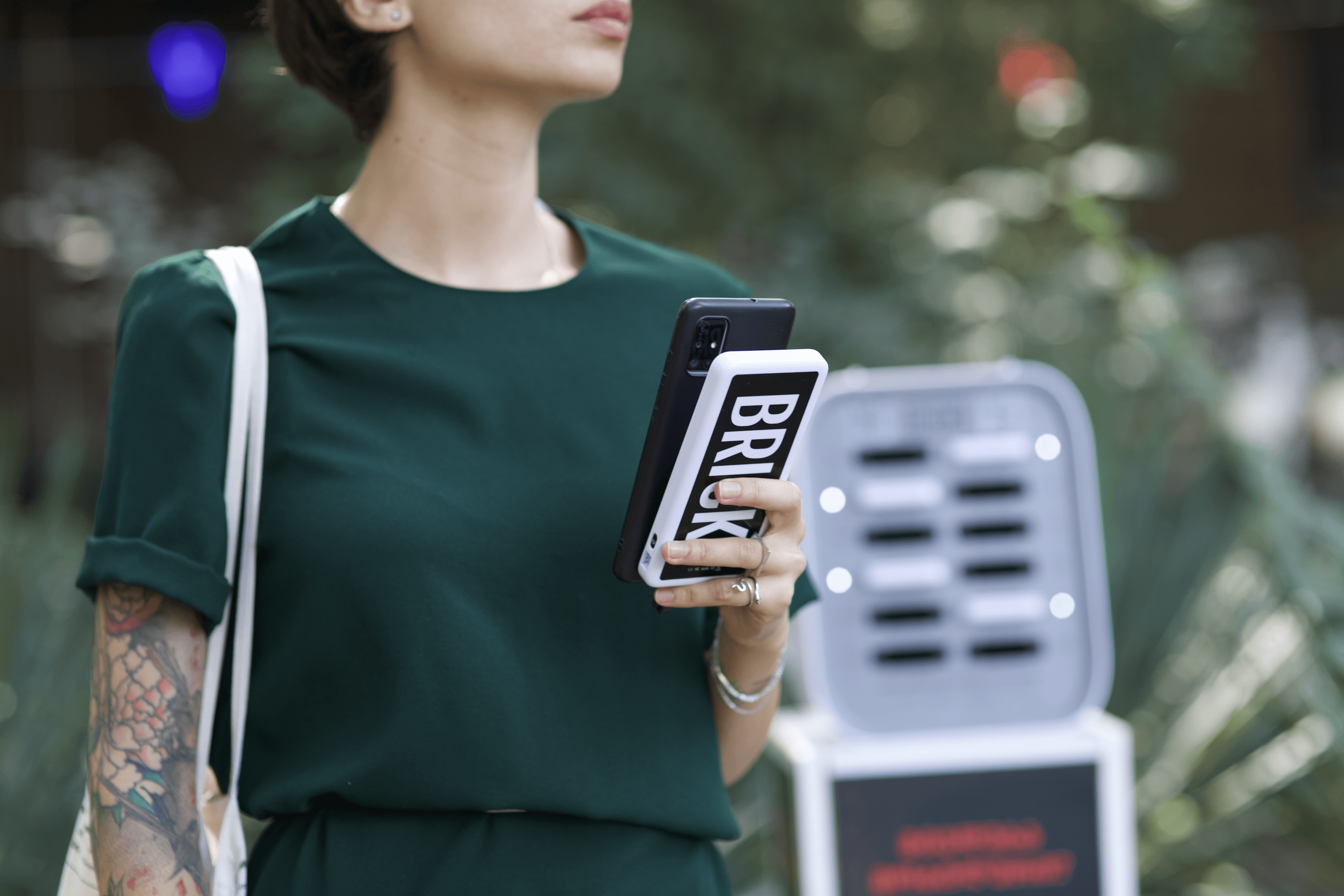 Una donna con in mano un power bank Brick davanti a una stazione di noleggio